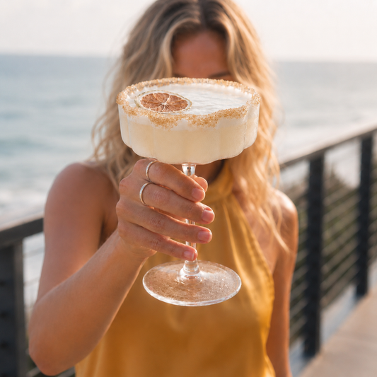 Woman holding a margarita cocktail with lime rim cocktail blend salts and dried lime garnish